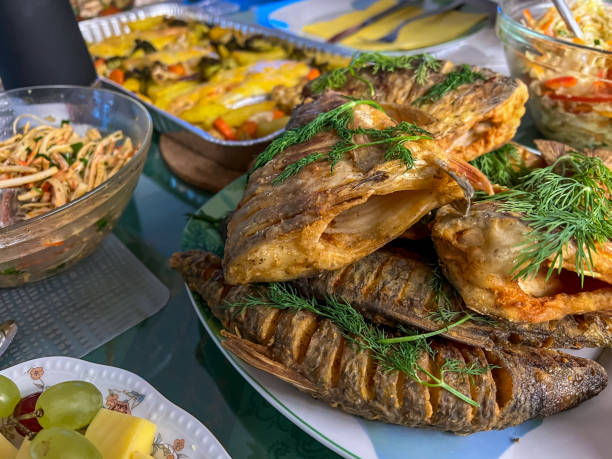 istock Delicious Christmas dinner with fish, vegetables, fruit and bread. 1369131692