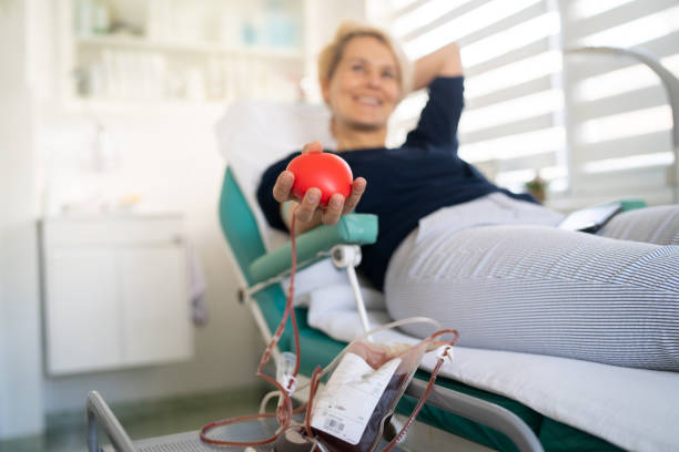 Happy woman is laying down while donating her blood stock photo