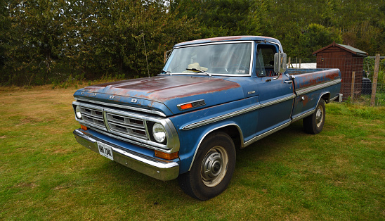 Upper Dean, Bedfordshire, England - September 07, 2019:  Classic Blue Ford F 250 Pickup parked isolated on park land.