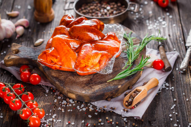 istock smoked chicken wings in a plastic package, spices, vegetables on a kitchen cutting board, dark and moody, clouseup on a black wooden isolated background, top 1369132735