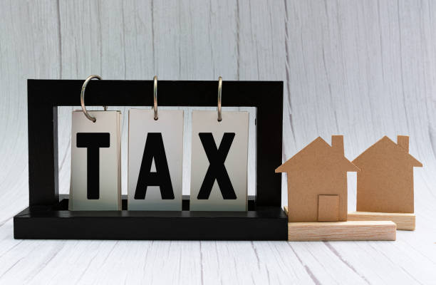 Tax text on paper stand black frame with house model on white wooden background stock photo