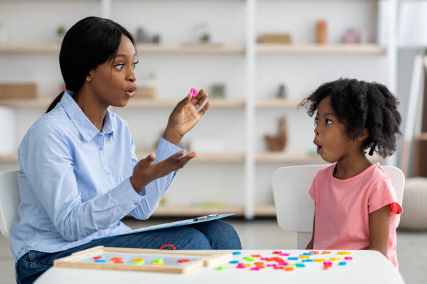 Speech therapist working with little black girl stock photo