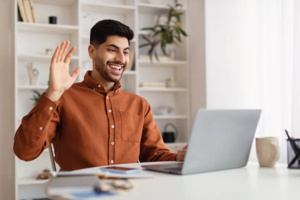 istock Arab man using laptop waving hand making video call 1369134961