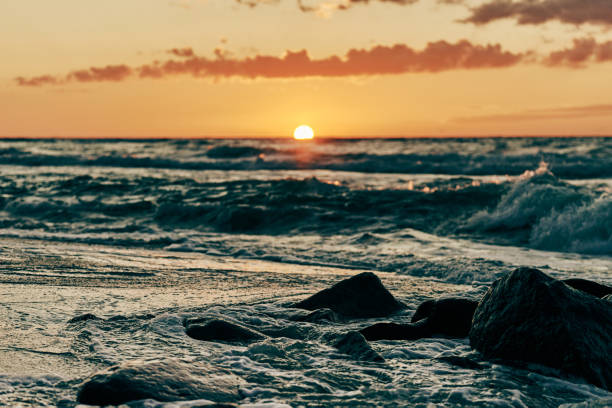 istock Yellow sun almost down horizon over deep blue sea, atmospheric view from rocky sea beach 1369136721