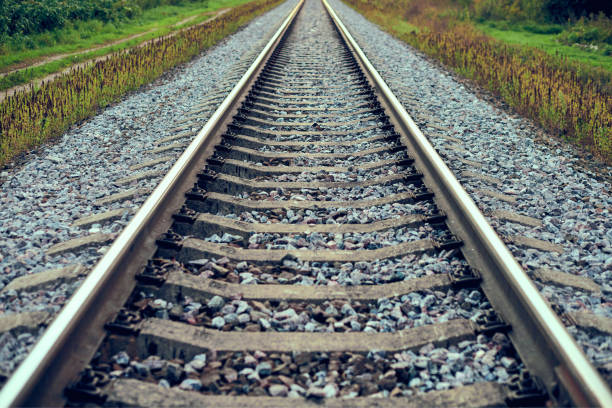 istock Railway track line going into distance, railroad train track with crushed stone, two parallel rails 1369136727