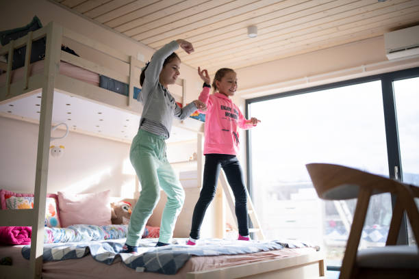 istock Cute little girls jumping on the bed. 1369141002