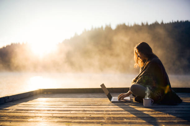 istock Young woman enjoying the sunrise and using laptop. 1369141008