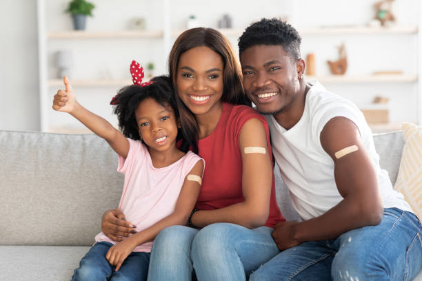 Vaccination Concept. Black Vaccinated Family Of Three With Adhesive Bandage On Arms Vaccination Concept. Portrait Of Black Vaccinated Family Of Three With Adhesive Bandage On Arms, Happy African American Mother, Father And Little Daughter Posing At Home After Covid-19 Vaccine Shot adhesive bandage photos stock pictures, royalty-free photos & images