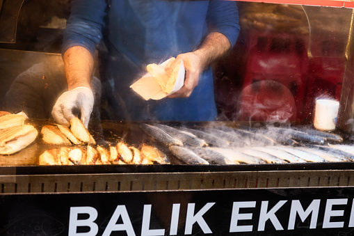 Chef making traditional turkish street food Balik Ekmek roasting mackerel filet in Istanbul, Turkey