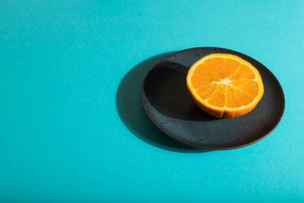 istock Ripe cut orange on blue ceramic plate on blue pastel background. Side view, copy space, hard light. 1369142751