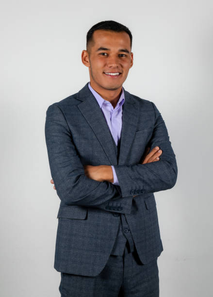 istock Young smiling man in a classic suit isolated on white background crossed hands 1369142907