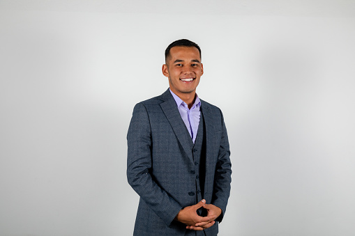 Young smiling man in a classic suit isolated on white background holding hands looking at the camera