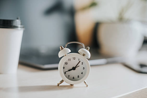 istock White alarm clock on the desktop in the office 1369143150