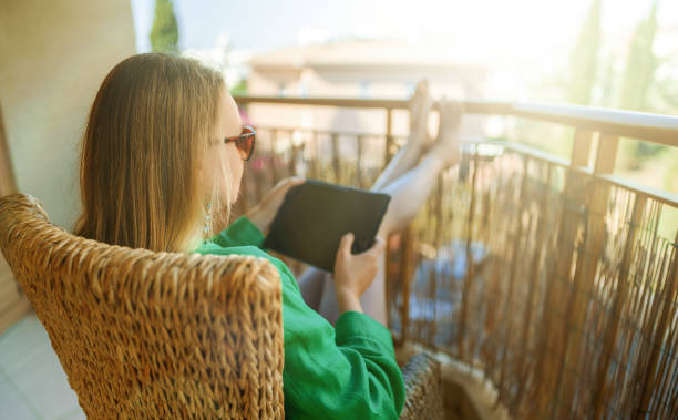 istock Woman with tablet pc enjoys summer on the balcony. 1369145801