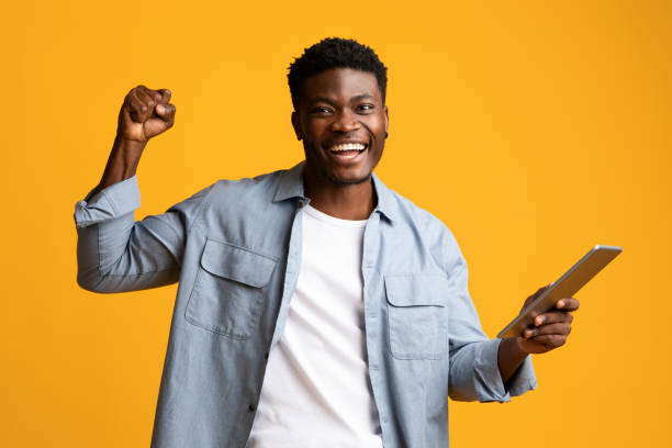 istock Happy african american guy sharing success, using pad 1369146246