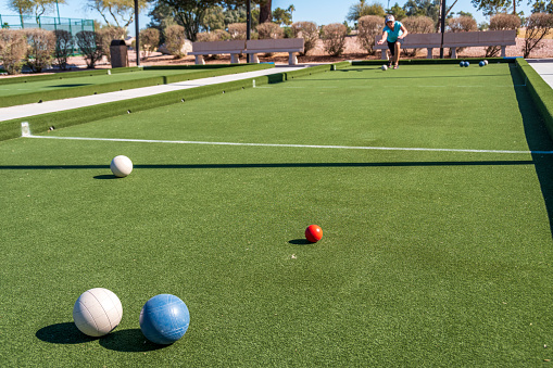 A senior woman playing bocce on artificial turf during the month of February in the state of Arizona.  The bocce courts are part of an adult resort community in the Sonoran Desert region.