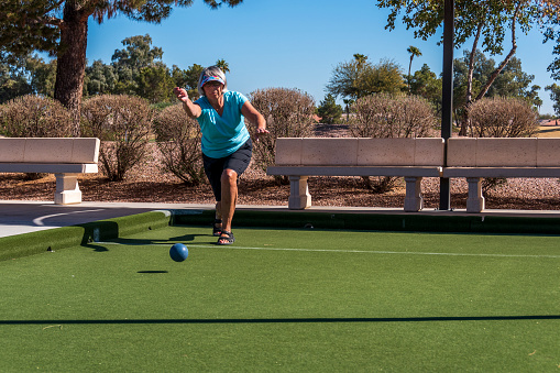 A senior woman playing bocce on artificial turf during the month of February in the state of Arizona.  The bocce courts are part of an adult resort community in the Sonoran Desert region.