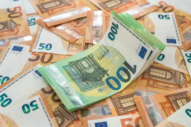 Photo of banknotes of 50 euros are laid out and on them are banknotes of 100 euros on the table