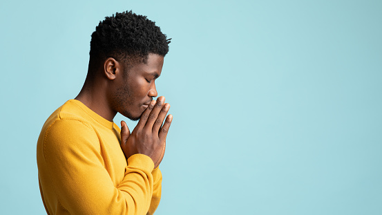 Vista lateral de un joven afroamericano rezando, espacio de copia photo