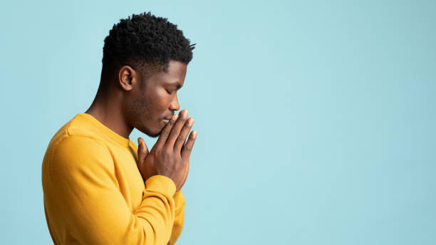 Side view of praying african american young man, copy space stock photo