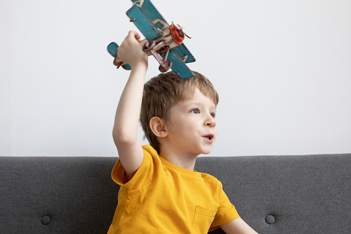 Boy plays on the sofa with a toy plane. Dream day.