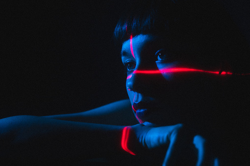 Portrait of young woman illuminated neon light and laser
