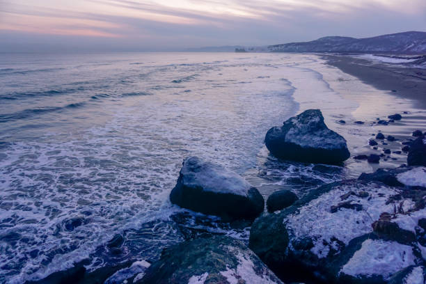 Incoming tide spreads a thin, foamy wash across the pebble beach on Taiwan's Pacific coast at Hualien. Textured foreground stones and a teal horizon create a cinematic east-coast seascape; no people.