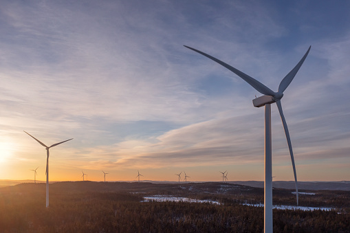 Wind power stations in sunlight in a winter forest landscape in the Dalarna region of Sweden.