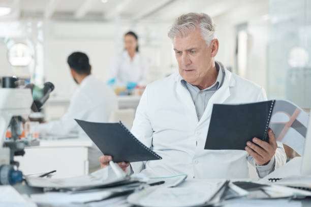 istock Shot of a mature scientist looking stressed out while going through paperwork in a lab 1369159140