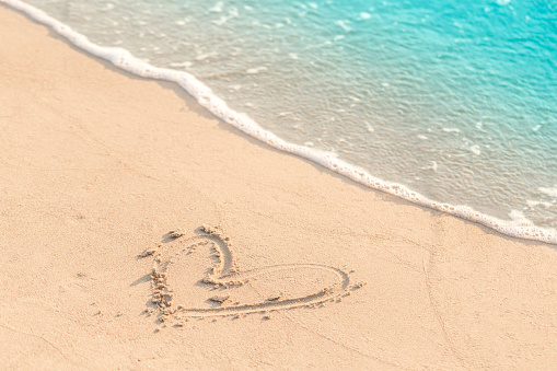 Heart drawn on sand near the sea