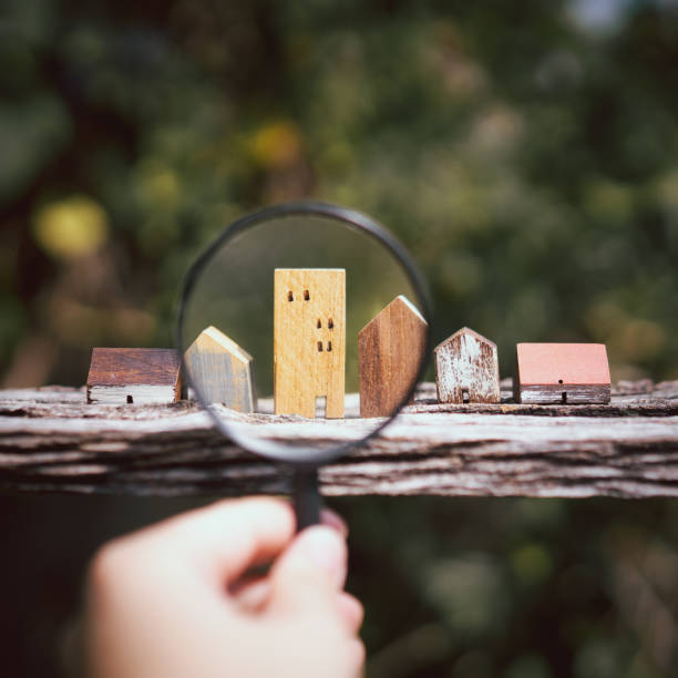 hand holding magnifying glass and looking at house model, house selection, real estate concept. - house human hand choice real estate imagens e fotografias de stock