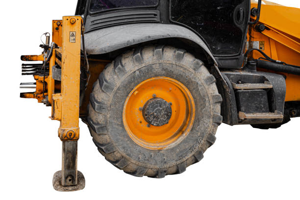 Big rubber wheels of soil grade tractor car earthmoving at road construction side. Close-up of a dirty loader wheel with a large tread with sky sunset stock photo