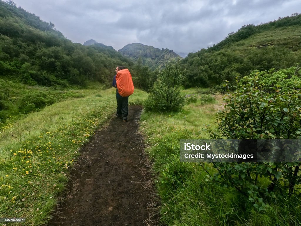 One man on a hiking trail in Iceland, trekking int he rain Beautiful panoramic Icelandic landscape of colorful volcanic Landmannalaugar mountains, at famous Laugavegur hiking trail. Active Lifestyle Stock Photo