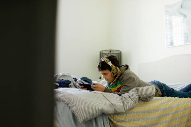 istock Pre teen plays game on messy bed 1369163086