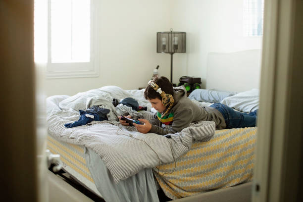 istock Pre teen plays game on messy bed 1369163092