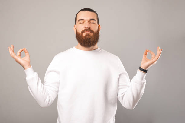 istock Positive bearded man is standing and holding hands up in zen gesture. 1369164562