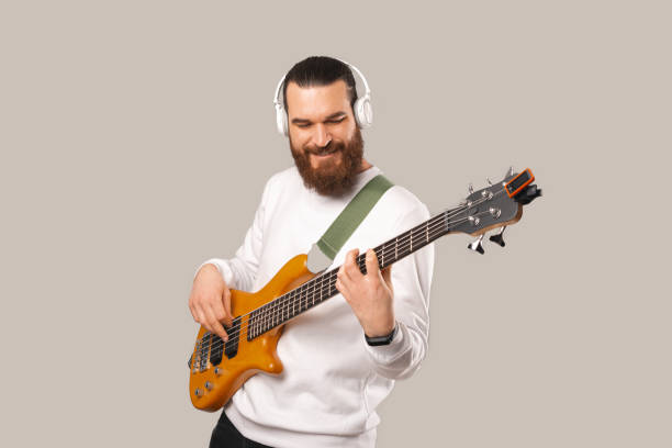 Photo of young handsome bearded man playing at bass guitar with 5 strings Photo of young handsome bearded man playing at bass guitar with 5 strings. bass instrument stock pictures, royalty-free photos & images