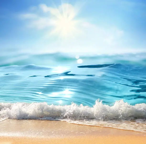 Summer landscape with sea surf, nature of tropical beach with rays of sun light. Golden sand beach, wave sea water, blue sky with white clouds. Copy space, summer vacation concept.