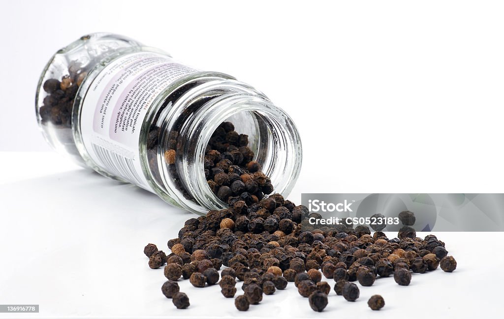 Hot balls. peppercorns pouring out of the bottle on white background. Black Peppercorn Stock Photo