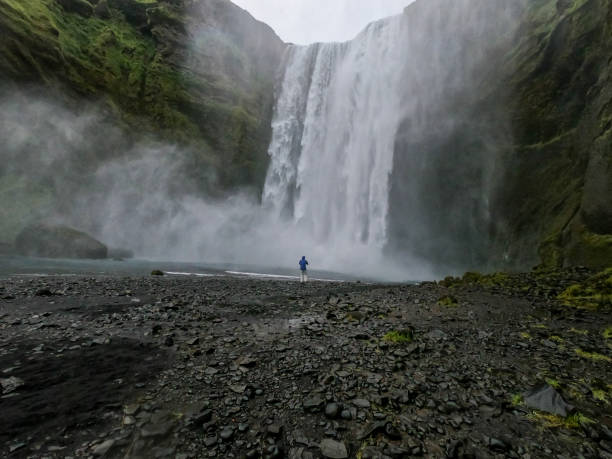 istock Man against large waterfall in Iceland 1369167868