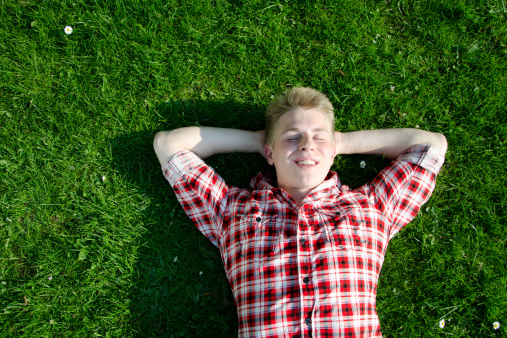 smiling young man lays on grassland.