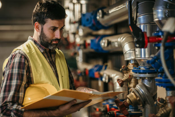 energy plant worker Hardworking energy plant worker in working suit and with protective helmet oil pump petroleum equipment development stock pictures, royalty-free photos & images