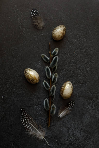 istock Happy Easter concept. Preparation for holiday. Golden decorated easter eggs willow feather on trendy grunge scratched dark black shale background. Simple minimalism flat lay top view, copy space 1369173841