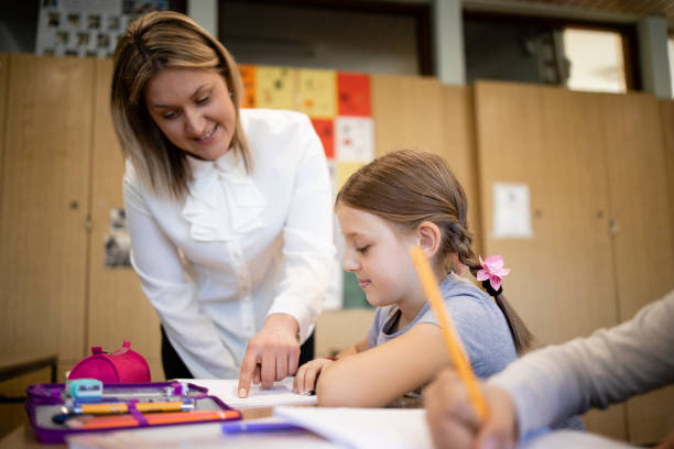 istock Caucasian schoolteacher helping children with their tasks in classroom. 1369176265