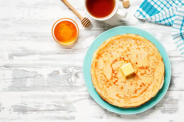Flat lay composition with fresh thin pancakes or crepes on white wooden table . Space for text