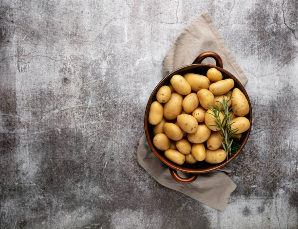 Raw small potatoes in a cast iron skillet on a beton background.