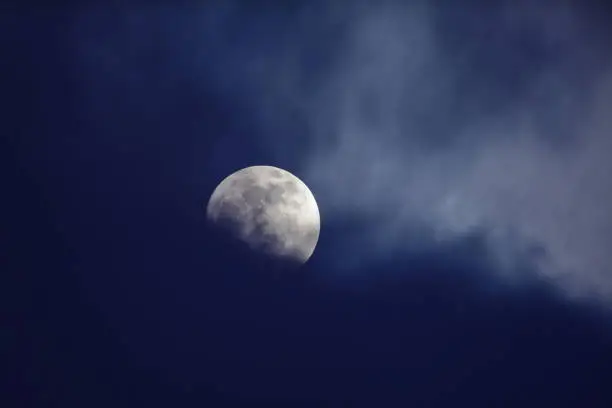 Photo of Moon behind dark blue clouds