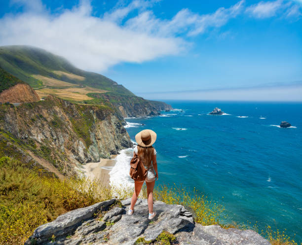 Girl on hiking trip resting on top of the mountain looking at ocean view. Woman relaxing on hiking trip by the Pacific ocean. Woman enjoying beautiful coastal scenery. People looking at beautiful ocean view. Pacific Ocean, Big Sur, California, USA big sur stock pictures, royalty-free photos & images