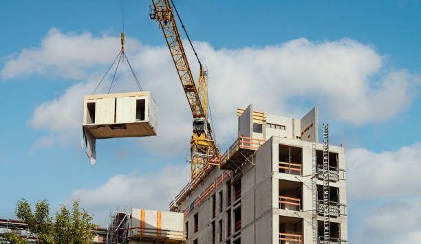 Crane lifting a wooden building module to its position in the structure.