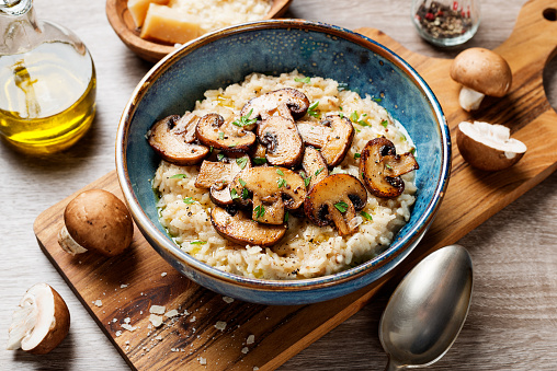 Risotto with brown champignon mushrooms on wooden background.
